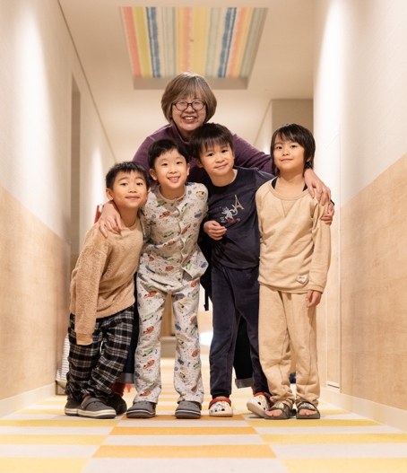 ボーディングハウスの廊下で先生と並ぶJINISの子どもたち